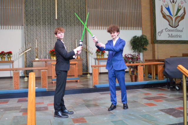 Two young men holding light sabers standing on the chancel of Central United Methodist Church in Waterford MI.