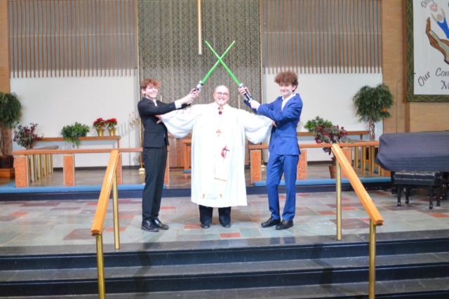 Two young men with light sabers crossed over the head of Pastor Jack of Central United Methodist Church in Waterford. MI