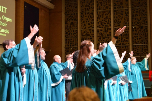 Choir members in robes holding their hands to the sky at Waterford Central United Methodist Church in Waterford MI