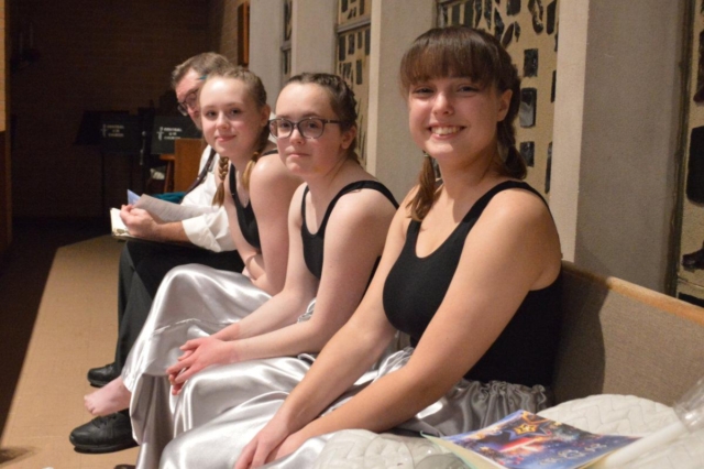 Three young women sitting backstage on a pew at Central United Methodist Church in Waterford MI