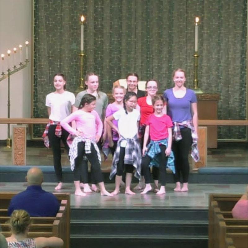 A group of kids in dance attire with flannel shirts posing at the end of their dance.