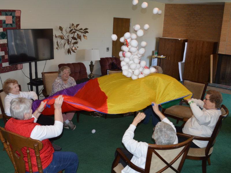 A group of older women playing a parachute game throwing balls in the air at Central UMC in Waterford, MI