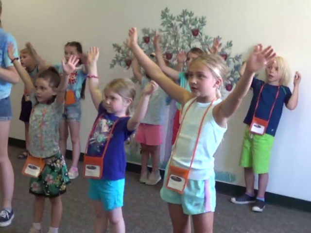 A group of girls holding their hands up as they dance at Central's summer VBS program in Waterford, MI